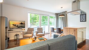 A modern living room with a sofa, chairs, a coffee table, and a TV mounted on the wall. - Villa Limora, apt. 04 (Heringsdorf)
