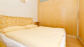 Une chambre à coucher avec un lit, une table de chevet et une armoire en bois.