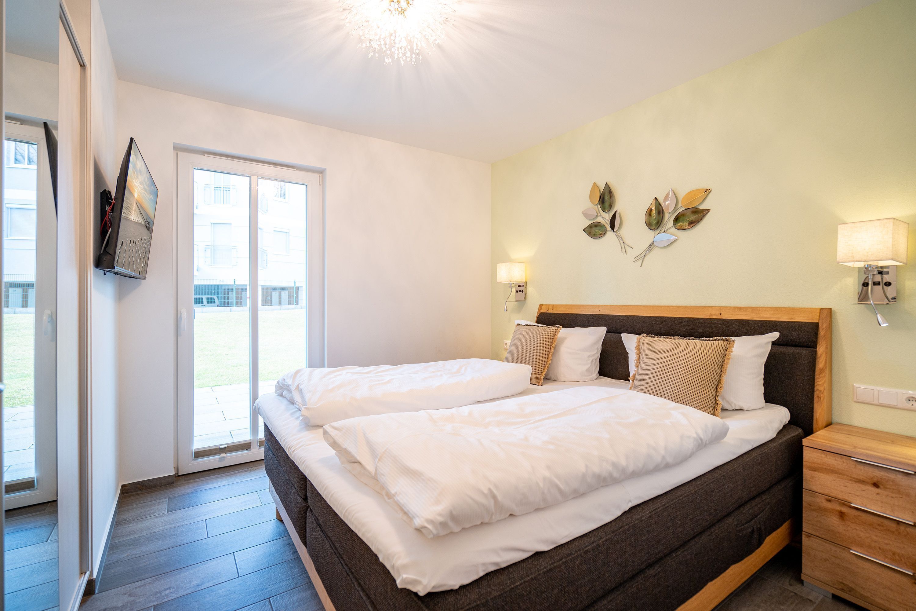 A double bed with a wooden headboard, two bedside tables, and a wall-mounted lamp.