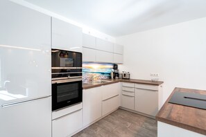 Une cuisine moderne avec des armoires blanches, des appareils en acier inoxydable et un plan de travail en bois.
