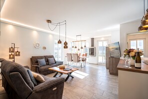 Un salon moderne avec un canapé, une table à manger et des luminaires suspendus.