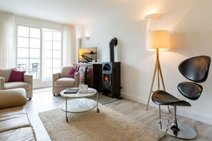 Un salon comprenant un canapé, des fauteuils, une table basse, une cheminée et un téléviseur.