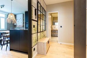 Una cucina moderna con isola centrale, zona pranzo con panchetta e vista sul bagno adiacente.