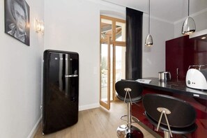 Una cocina moderna con un refrigerador negro, una zona de comedor con dos taburetes de bar y una pared decorada en rojo.