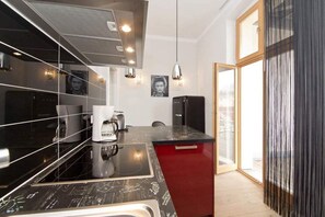 Una cocina moderna con encimera negra, armarios rojos y un amplio ventanal.