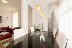 Una habitación moderna con una mesa de vidrio, un sofá rojo y vistas a un paisaje urbano a través de una ventana.
