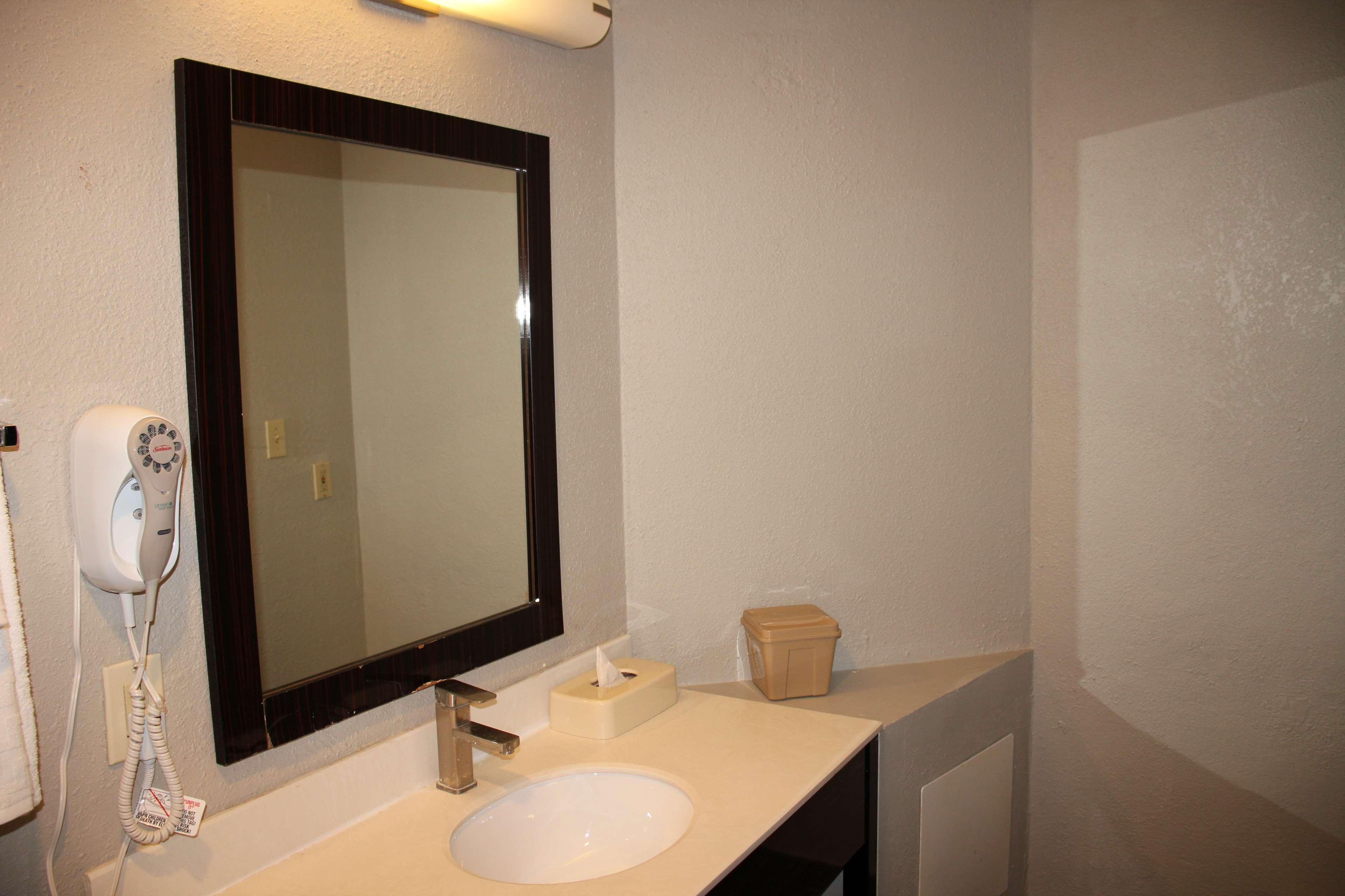 A bathroom with a sink, mirror, hairdryer, and a tissue box.