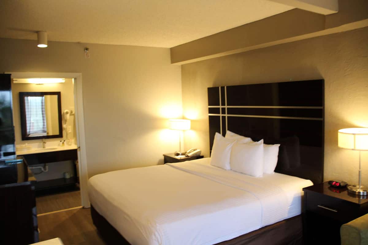 Camera d'albergo con un grande letto, lampade sui comodini, un comodino, una scrivania e uno specchio.
