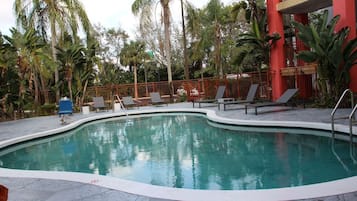 A swimming pool with lounge chairs and a red building in the background.