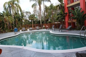 A swimming pool with lounge chairs and a red building in the background. - Boca Suites Deerfield Beach Surestay Collection BW (Deerfield Beach)