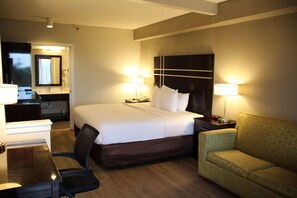Une chambre d’hôtel avec un lit, des lampes de chevet, un bureau, une chaise et un canapé.