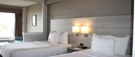 Une chambre d’hôtel avec deux lits, une table de chevet avec un téléphone et deux lampes fixées au mur.