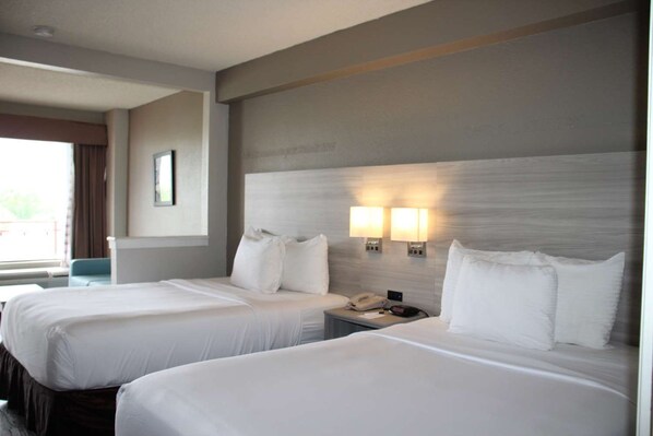 A hotel room with two beds, a nightstand with a phone, and two wall-mounted lamps. - Boca Suites Deerfield Beach Surestay Collection BW (Deerfield Beach)
