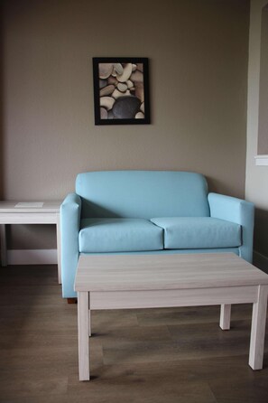 A light blue sofa, a white coffee table, and a framed picture on the wall.