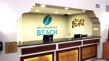 A reception desk with a sign for Boca Suites Deerfield Beach.