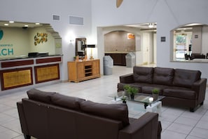 A reception area with a counter, a wooden cabinet, and two brown sofas. - Boca Suites Deerfield Beach Surestay Collection BW (Deerfield Beach)