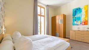 A hotel room with a large bed, a wardrobe, and a painting on the wall.
