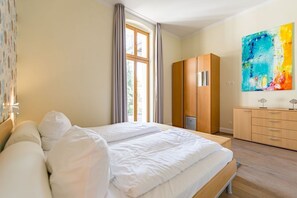 Quarto de hotel com uma cama grande, um guarda-roupa e um quadro na parede.
