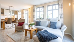 A modern living room with a sofa, chairs, a coffee table, and a dining area with a table and chairs. - Haus am Kliff, App. 9 (Heringsdorf)