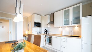 A modern kitchen with white cabinets, a wooden countertop, a built-in oven, and a sink. - Haus am Kliff, App. 9 (Heringsdorf)