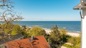 A coastal view from a building with a red-tiled roof, overlooking a beach and the sea. - Haus am Kliff, App. 9 (Heringsdorf)