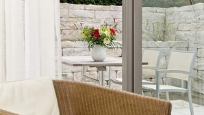 En fletsofa med en hvid pude, en hvid vase med blomster og en stenvæg i baggrunden.