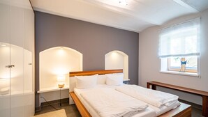 Ein modernes Schlafzimmer mit einem Holzbett, Nachttischlampen, einem Fenster mit Blick und einer eingebauten Bank.
