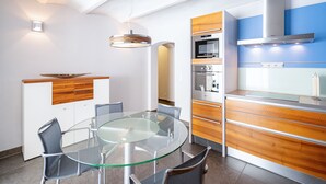 Eine moderne Küche mit einem Glastisch, Holzschränken und Edelstahlgeräten.