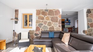 Ein modernes Wohnzimmer mit einer Wand aus Stein, einem Ledersofa und einem Holztisch.