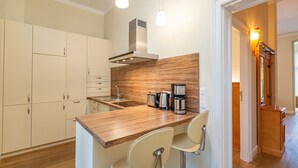Une cuisine moderne dotée de plans de travail en bois, d’appareils électroménagers en acier inoxydable et d’un coin bar avec deux tabourets.