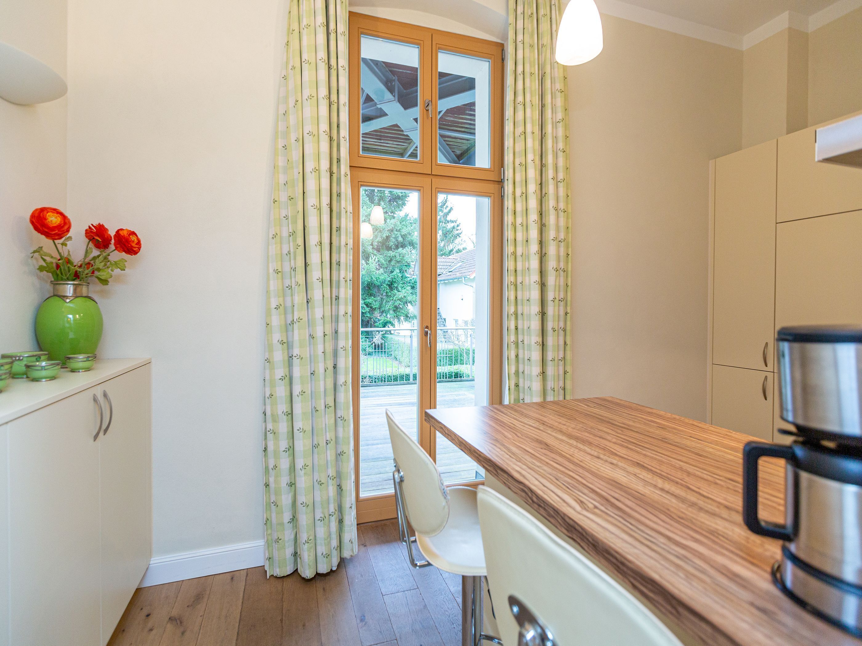 A kitchen with a wooden countertop, a coffee maker, and a view of a balcony with a railing.