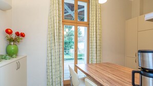 Une cuisine dotée d’un plan de travail en bois, d’une machine à café et offrant une vue sur un balcon avec une balustrade.