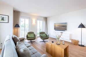 A modern living room with a sofa, two armchairs, a wooden coffee table, and a TV. - Domizil Meerzeit, App. 3 (Heringsdorf)