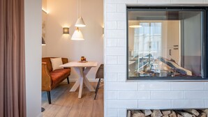A modern interior with a white brick fireplace, a wooden table, a sofa, and pendant lighting. - Domizil Meerzeit, App. 4 (Heringsdorf)