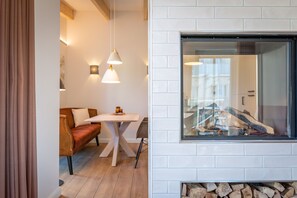 A modern interior with a white brick fireplace, a wooden table, a sofa, and pendant lighting.