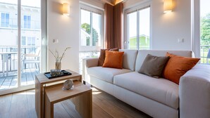 A modern living room with a sofa, a coffee table, and a view of the outside. - Domizil Meerzeit, App. 4 (Heringsdorf)