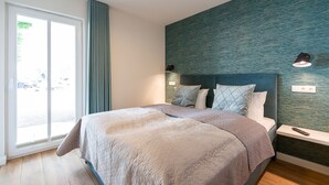 Un dormitorio moderno con una cama grande, una mesita de noche y vistas a través de un ventanal corredera.