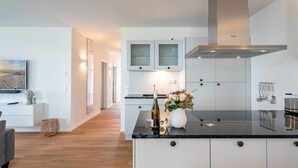 Una cocina moderna con armarios blancos, encimera negra y campana extractora de acero inoxidable.