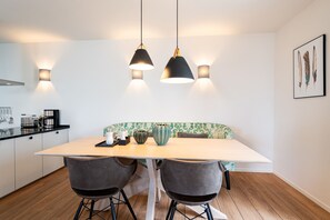 Une cuisine moderne avec une table en bois, deux chaises, un banc et des luminaires suspendus.