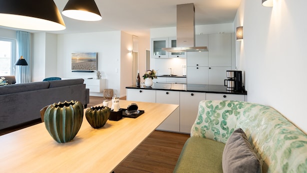 Una cocina moderna con comedor, que incluye lámparas colgantes, un sofá y una máquina de café.