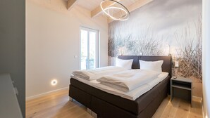Ein Schlafzimmer mit einem Bett, einem Nachttisch und einer Wand mit strukturierter Gestaltung.