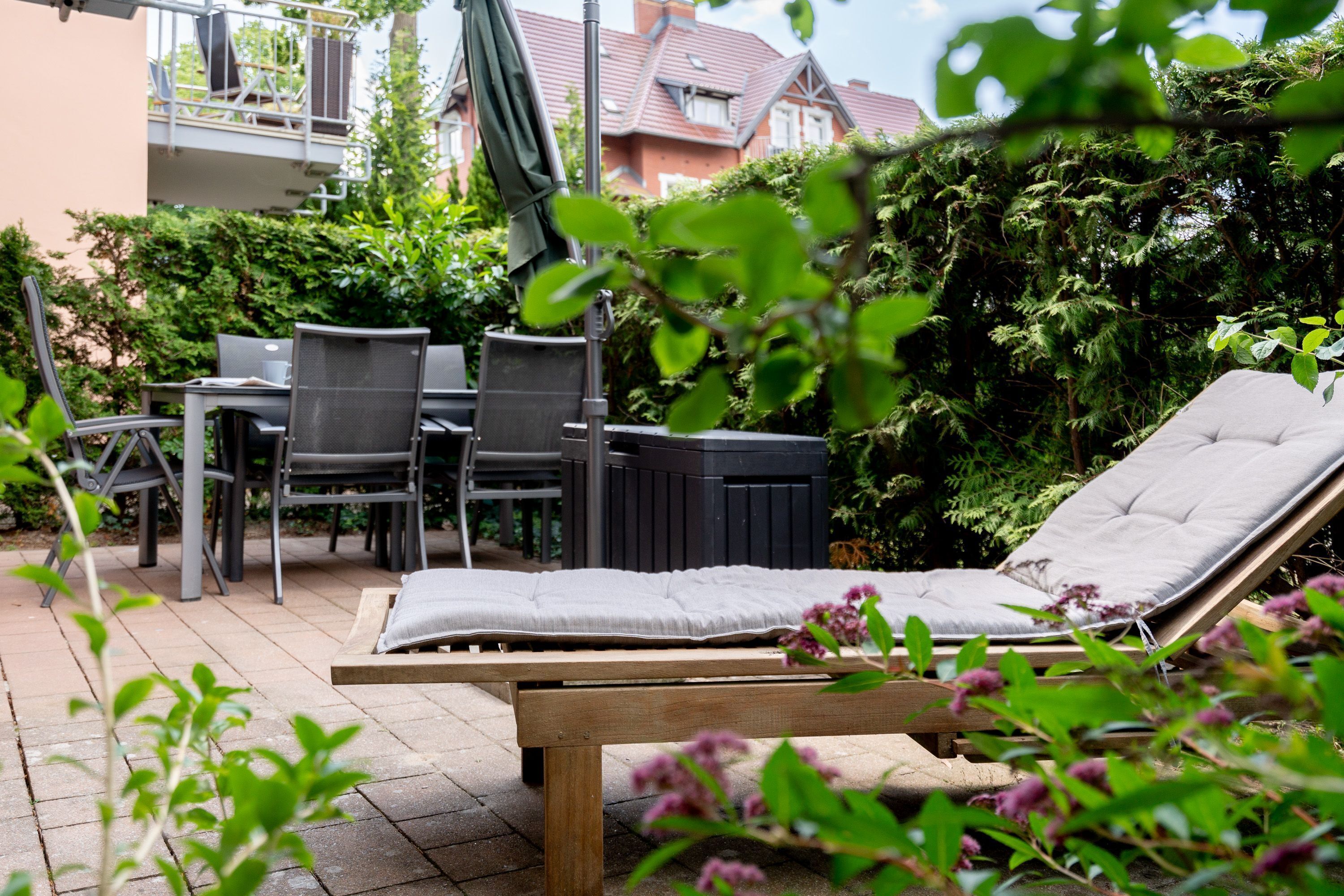 Eine Terrasse mit Holztisch und -stühlen, einem gepolsterten Liegestuhl und einem Whirlpool.