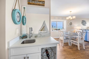 A kitchen with a sink, a small sailboat model, and a dining area with a table and chairs.