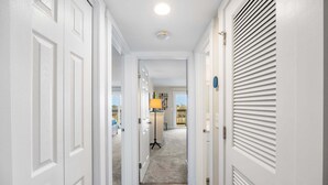 Un couloir avec des portes blanches, un luminaire au plafond et un sol recouvert de moquette.
