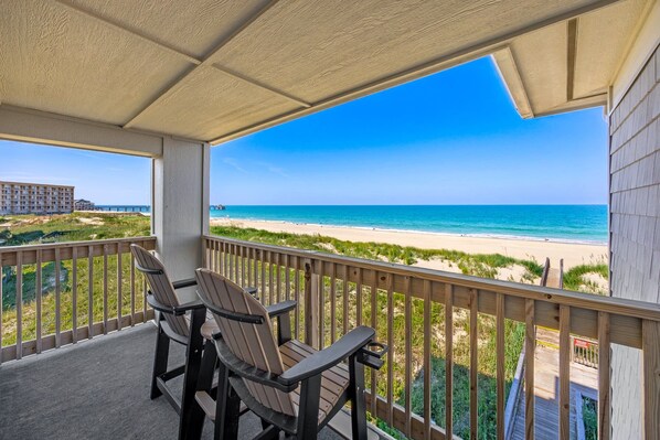 A balcony with two chairs and a view of the beach.