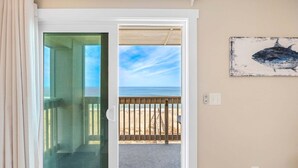Une pièce dotée d’une porte vitrée donnant sur un balcon avec vue sur la plage.
