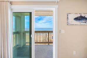 Ein Zimmer mit Glastür und Zugang zu einem Balkon mit Meerblick.