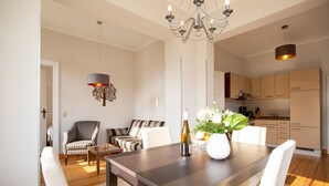 A modern dining area with a wooden table, white chairs, a chandelier, and a decorative wall piece. - House on the Hill, The Classic 03 (Heringsdorf)