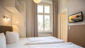 A hotel room with a bed, a window with curtains, a wall-mounted TV, and a view of a pier. - House on the Hill, The Classic 03 (Heringsdorf)