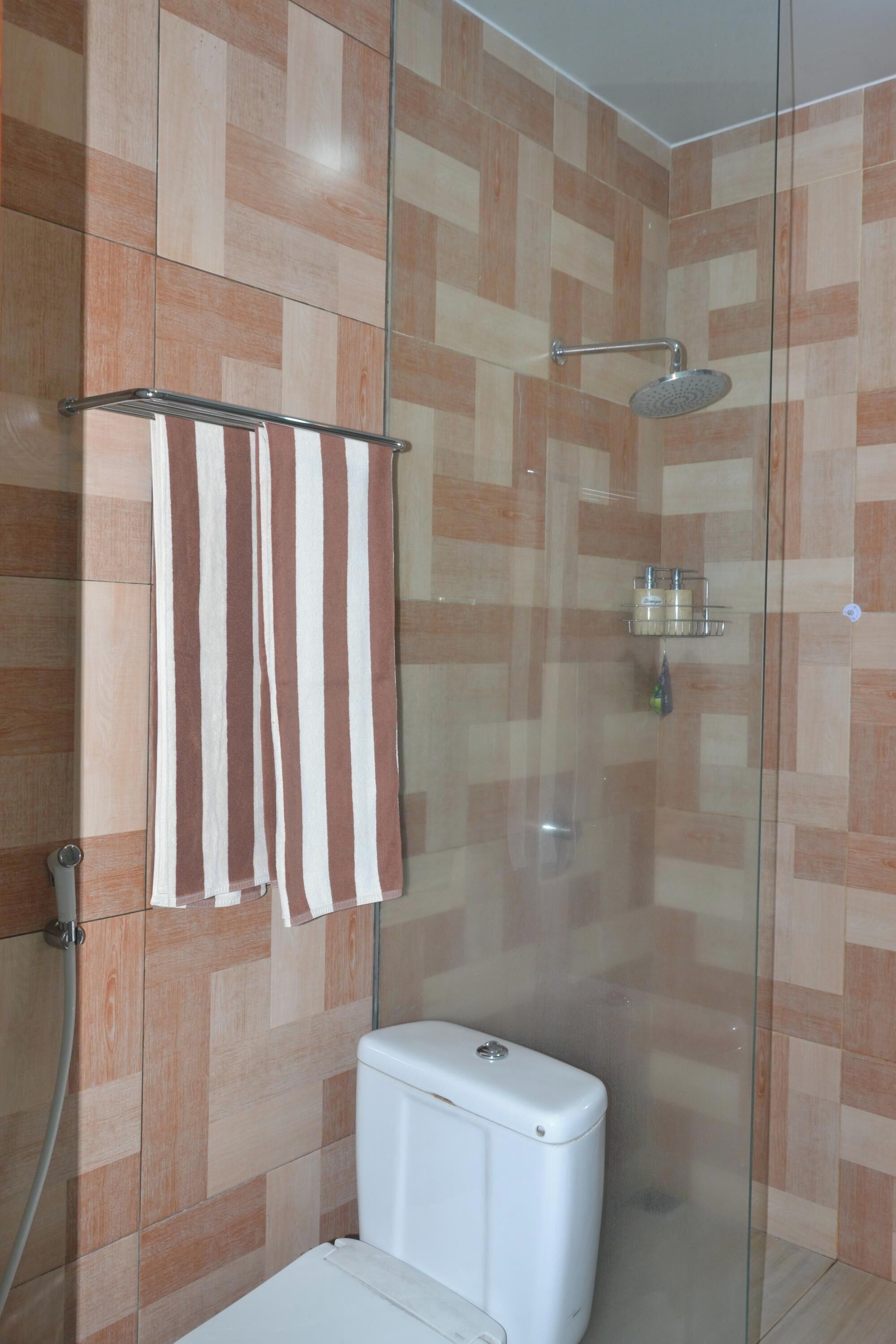 Ein Badezimmer mit einer Duschkabine, einer Toilette und einem Handtuchhalter mit gestreiften Handtüchern.